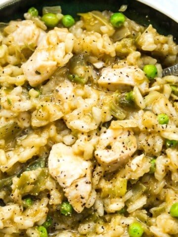 A bowl of chicken and leek risotto with a spoon in it.