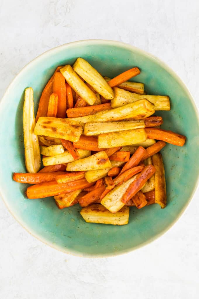 A bowl filled wth roasted carrots and parsnips.