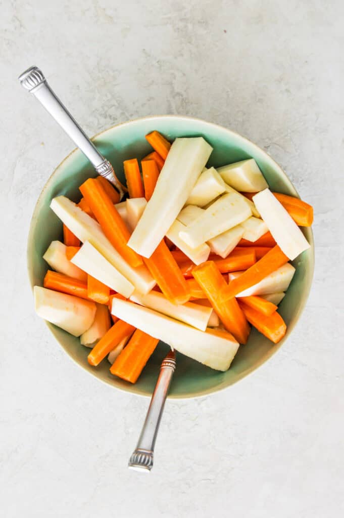 A bowl filled with chopped and peeled carrots and parsnips.