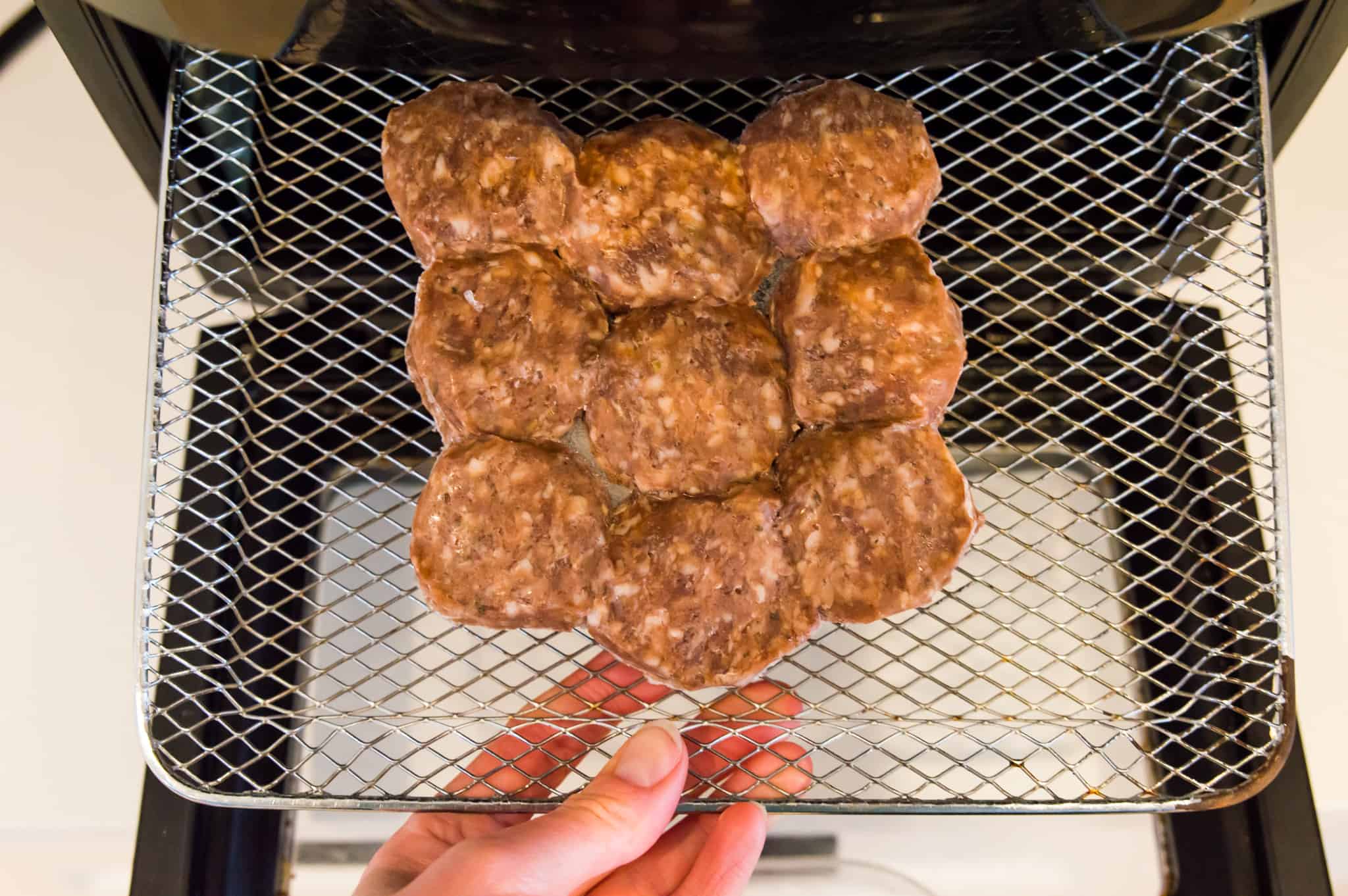 A batch of frozen meatballs on the tray of an air fryer