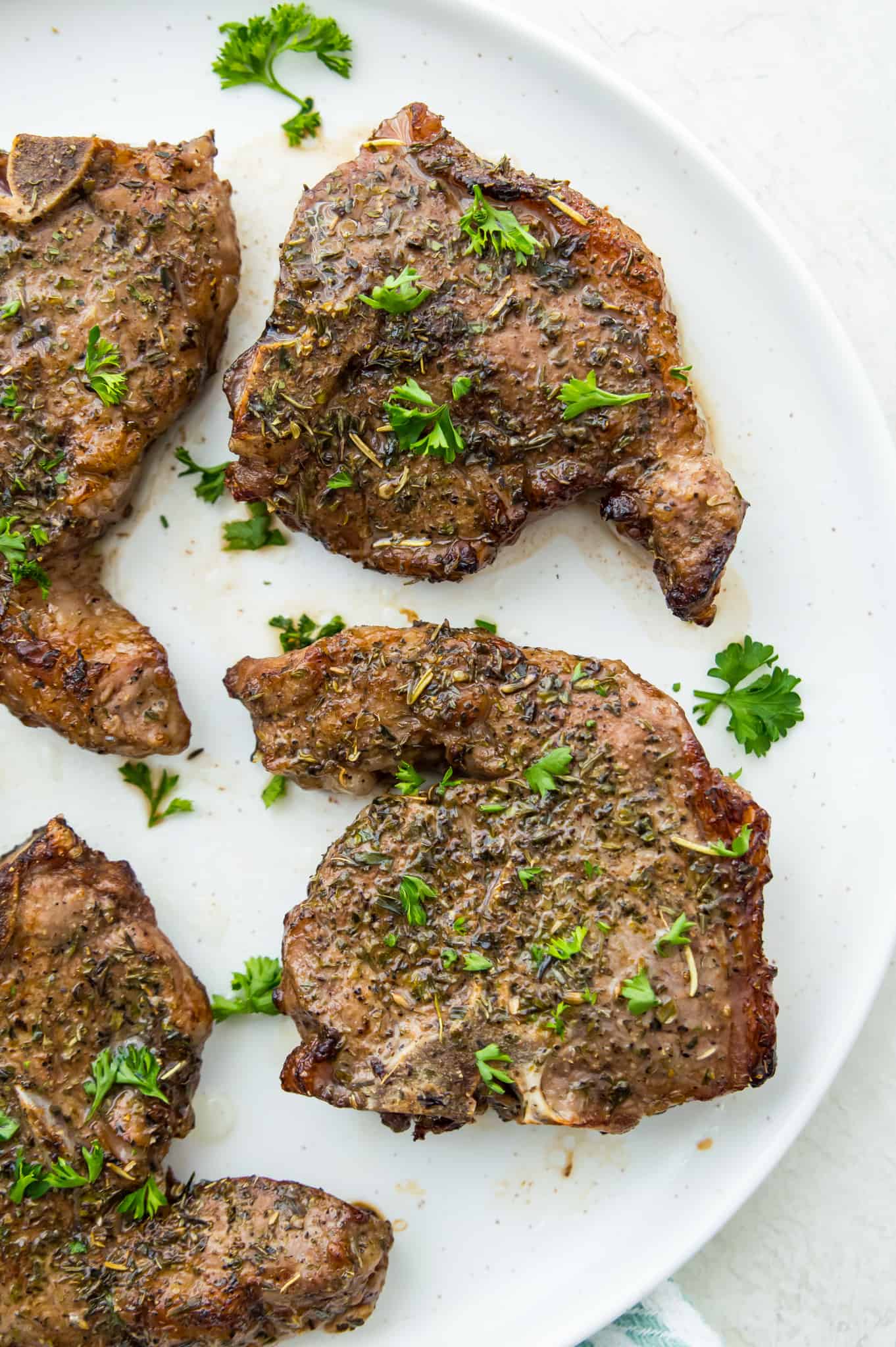 Cooked lamb chops on a plate garnished with fresh parsley.