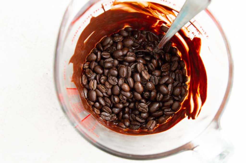 A glass measuring cup with melted chocolate and coffee beans in it.