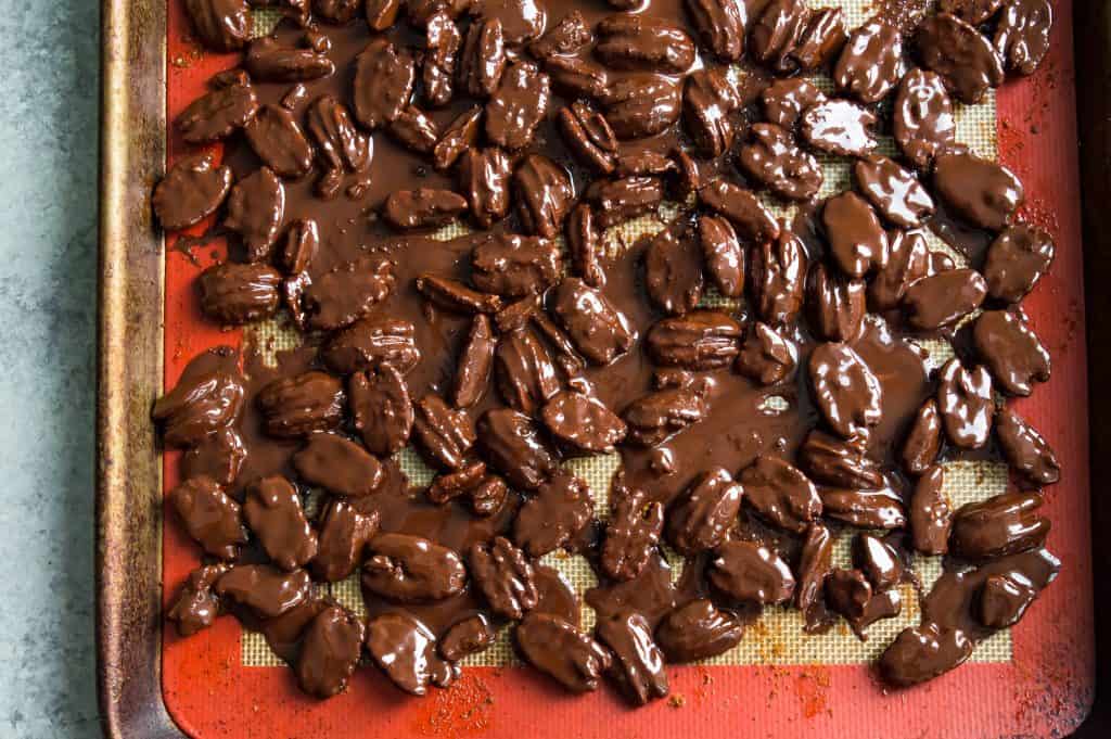 A baking sheet with chocolate covered pecans on it