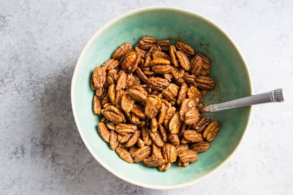 A bowl filled with pecans and a spoon.