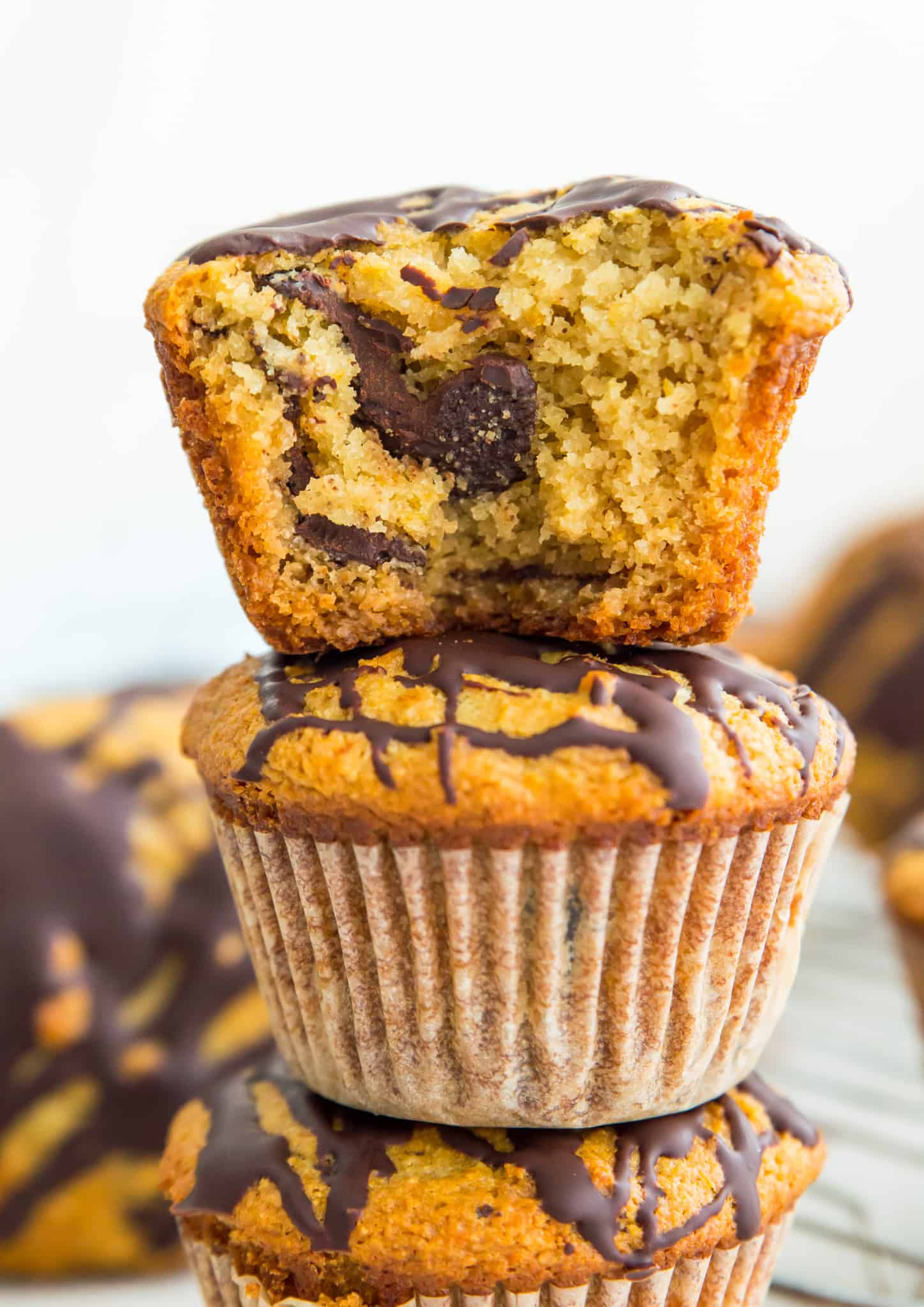Paleo orange chocolate chunk muffins stacked in a pile with a bite out of the top one.