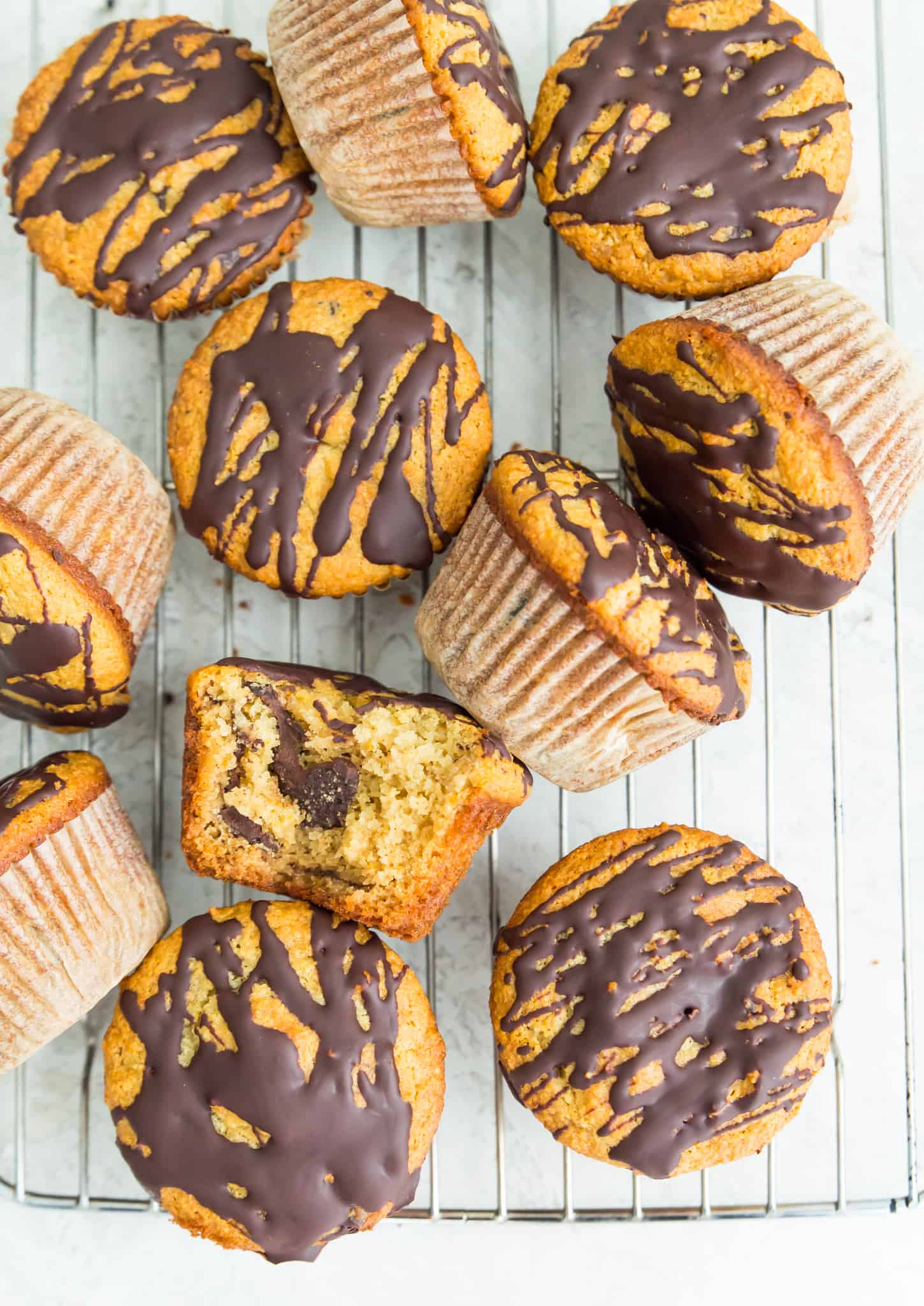 Paleo orange chocolate muffins on a rack with a bite out of one of the muffins.
