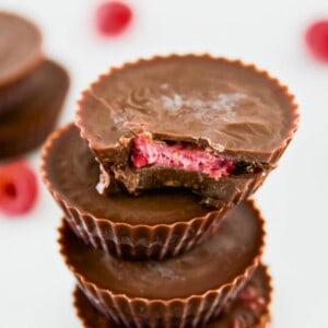 A stack of chocolate raspberry cups and the top one has a bite out of it.