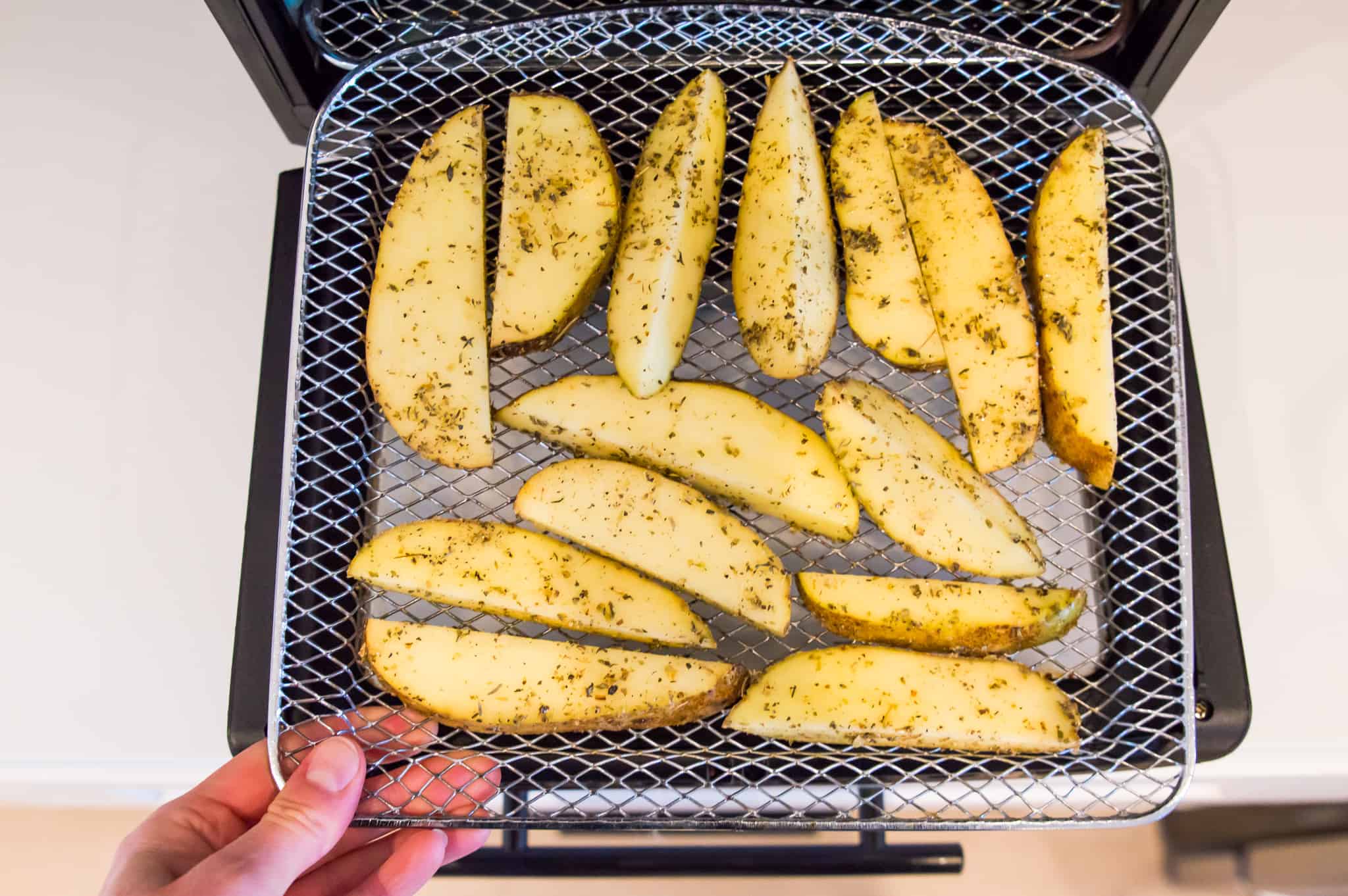 Sliced potatoes on an air fryer tray.
