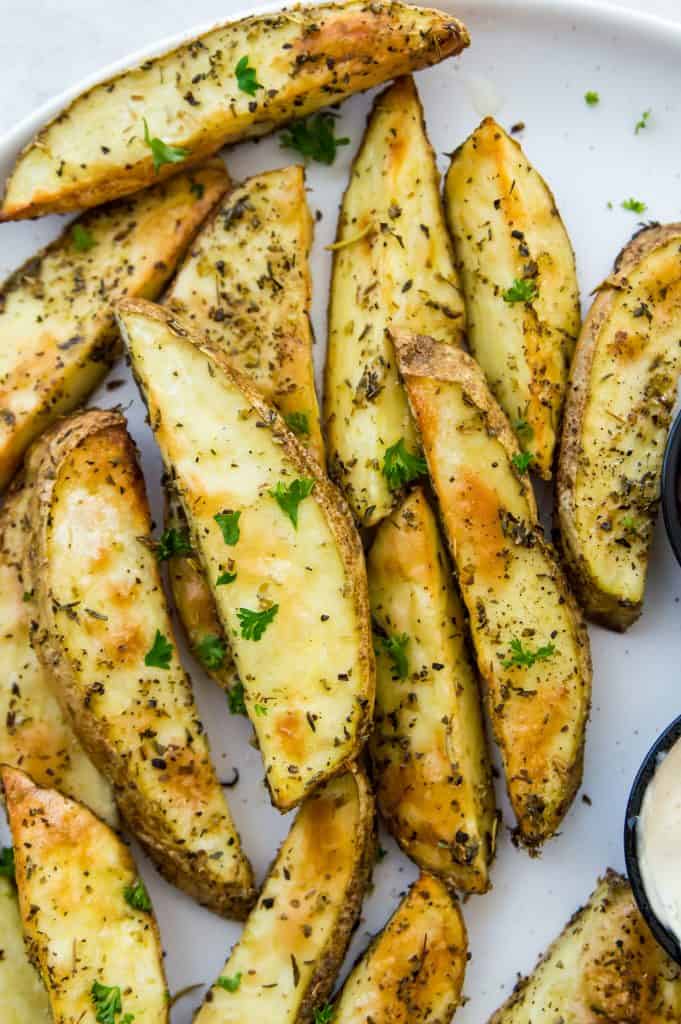 A plate of air fryer potato wedges seasoned with fresh parsley 