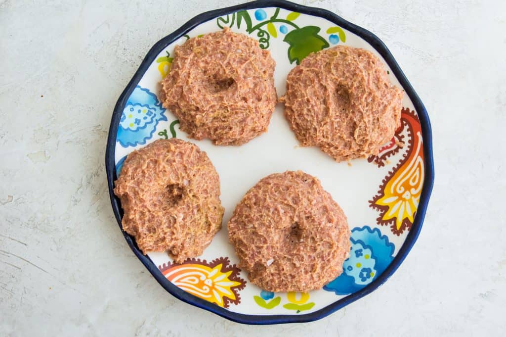 Uncooked turkey burger patties on a plate. 