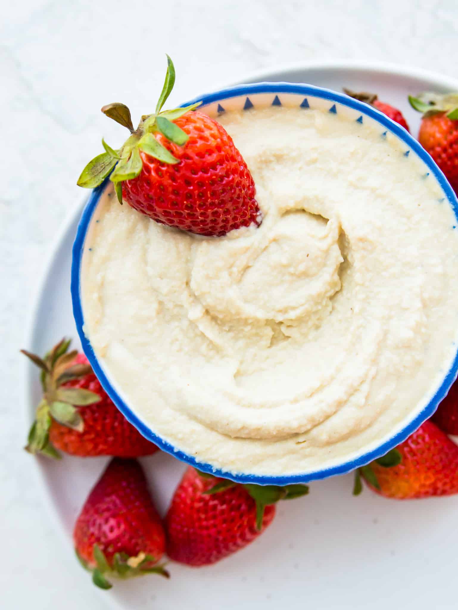 A bowl of vegan mascarpone with a fresh strawberry in it.