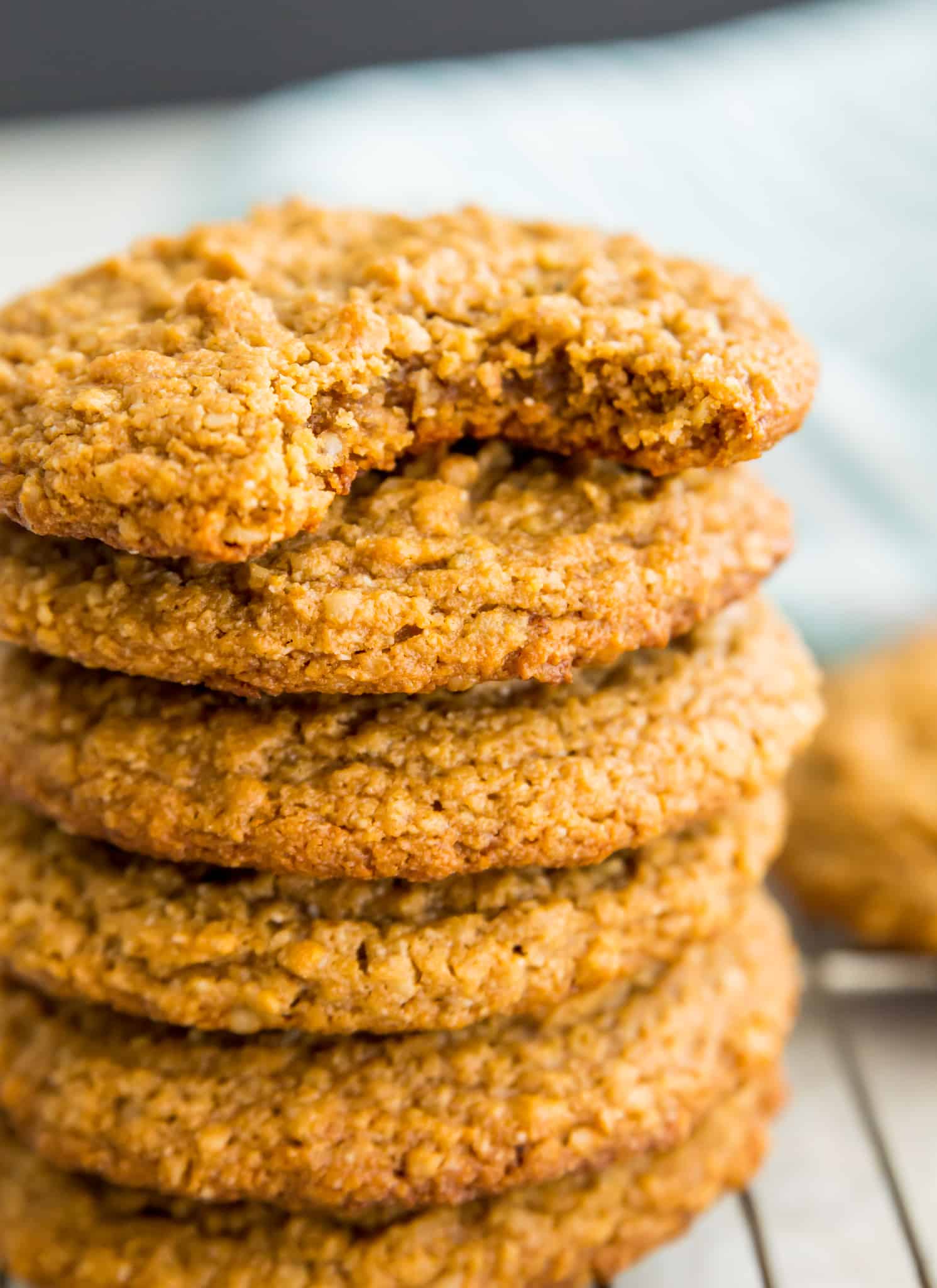 A stack of vegan peanut butter oatmeal cookies and the top cookies has a bite out of it.