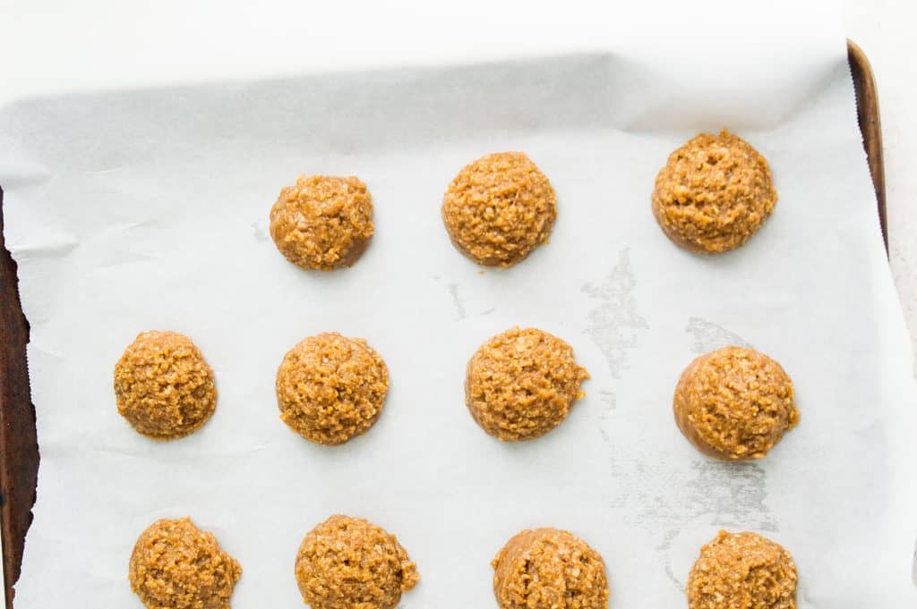 Cookie dough balls on a baking sheet lined with parchment paper. 
