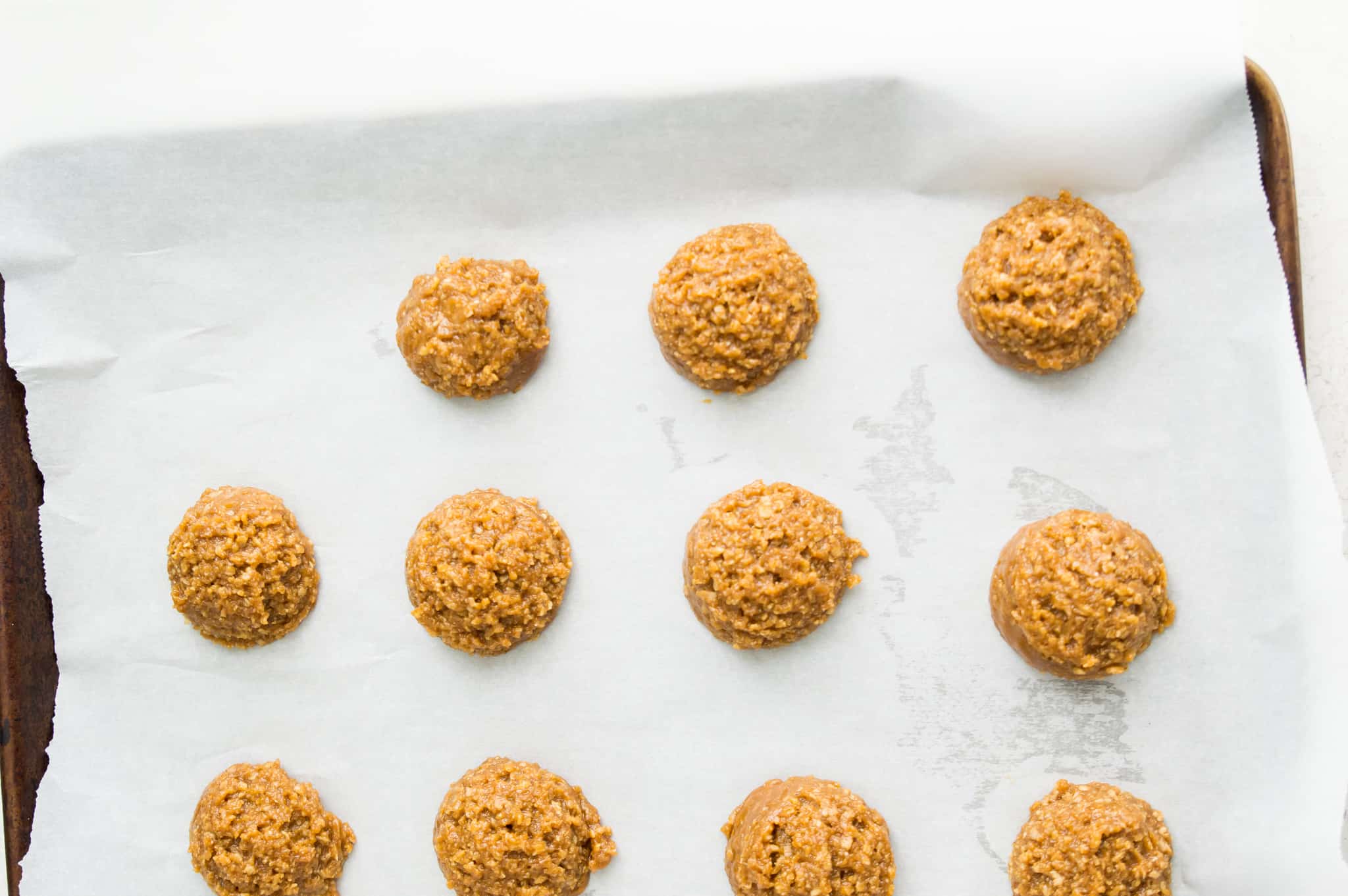 Cookie dough balls on a baking sheet lined with parchment paper.