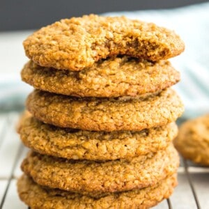A stack of vegan peanut butter oatmeal cookies and the top one has a bite out of it.