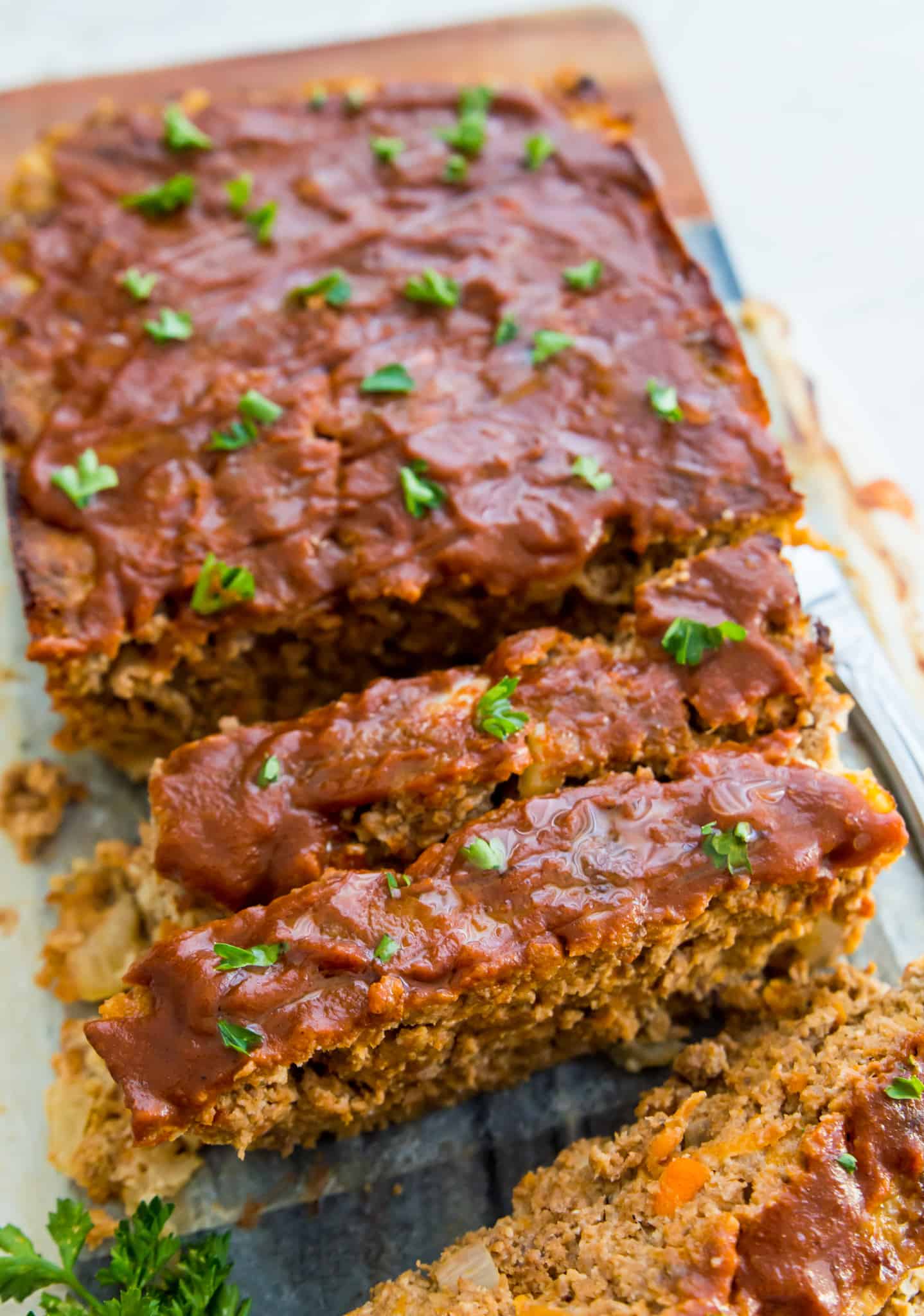 A meatloaf topped with barbecue sauce that a is cut into pieces. 