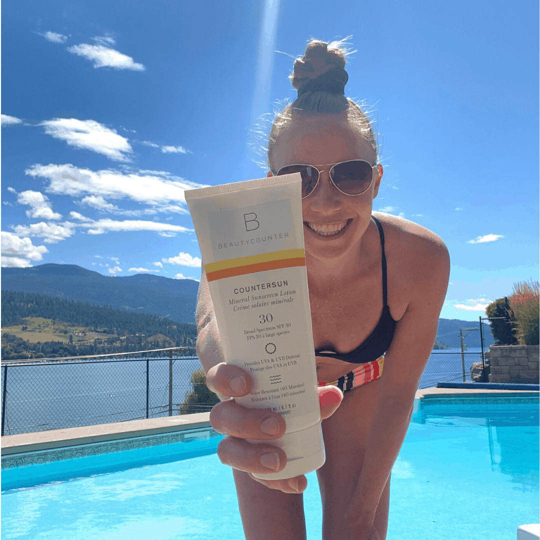 A girl in a bikini holding a bottle of Beautyconter SPF cream.