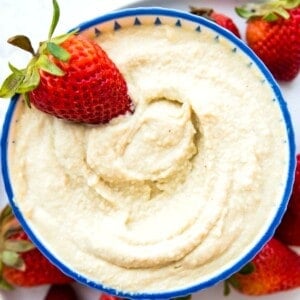 A bowl of vegan mascarpone with a fresh strawberry in it.