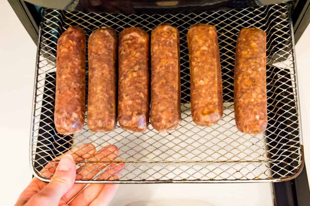 Six Italian sausages on an air fryer tray.