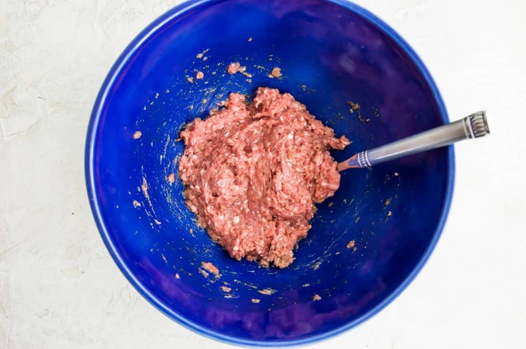 Ground duck meat in a bowl with a spoon.