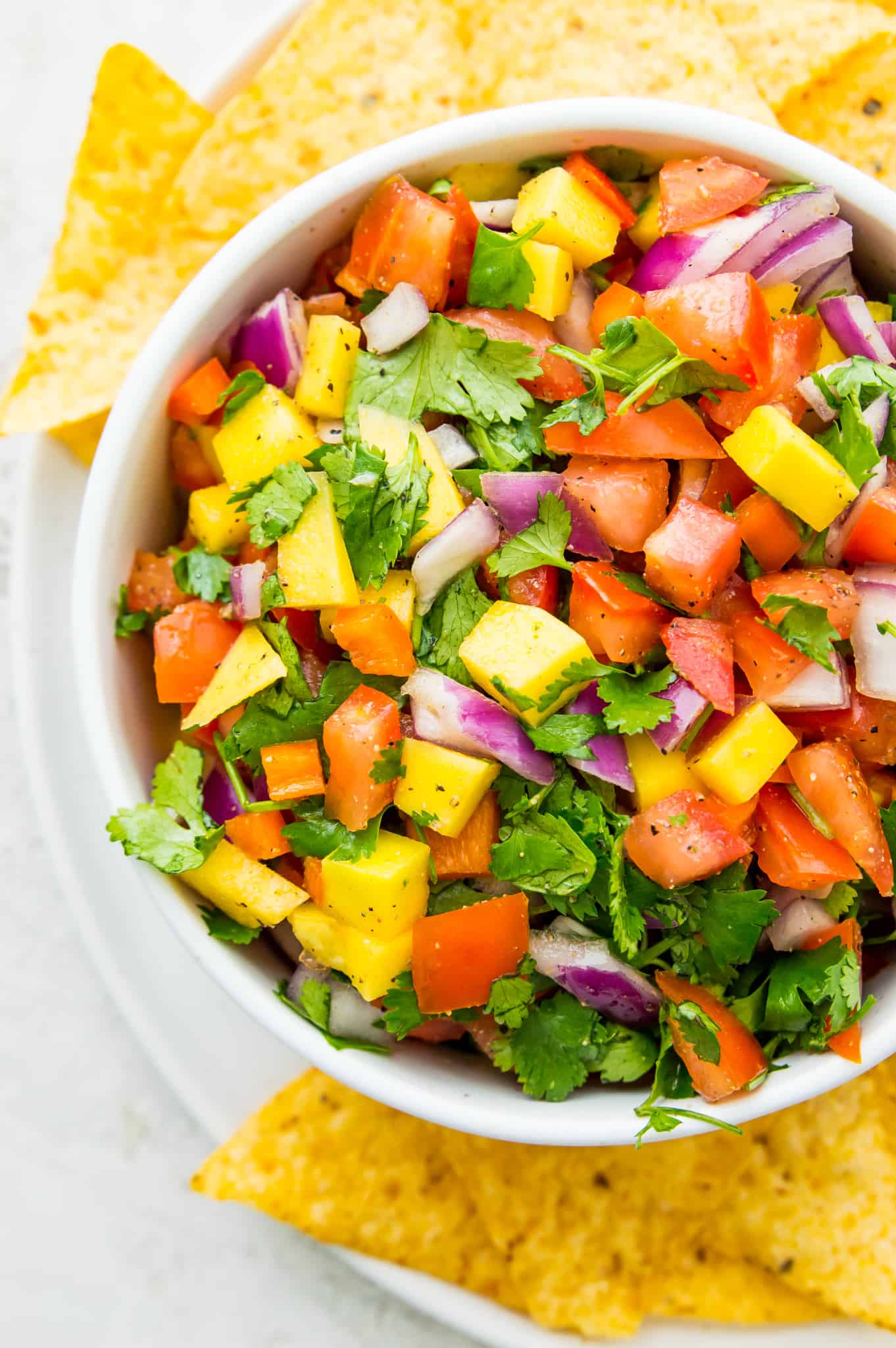 Mango Habanero Salsa A bowl of mango habanero salsa with red onion, tomatoes, cilantro, and pepper.