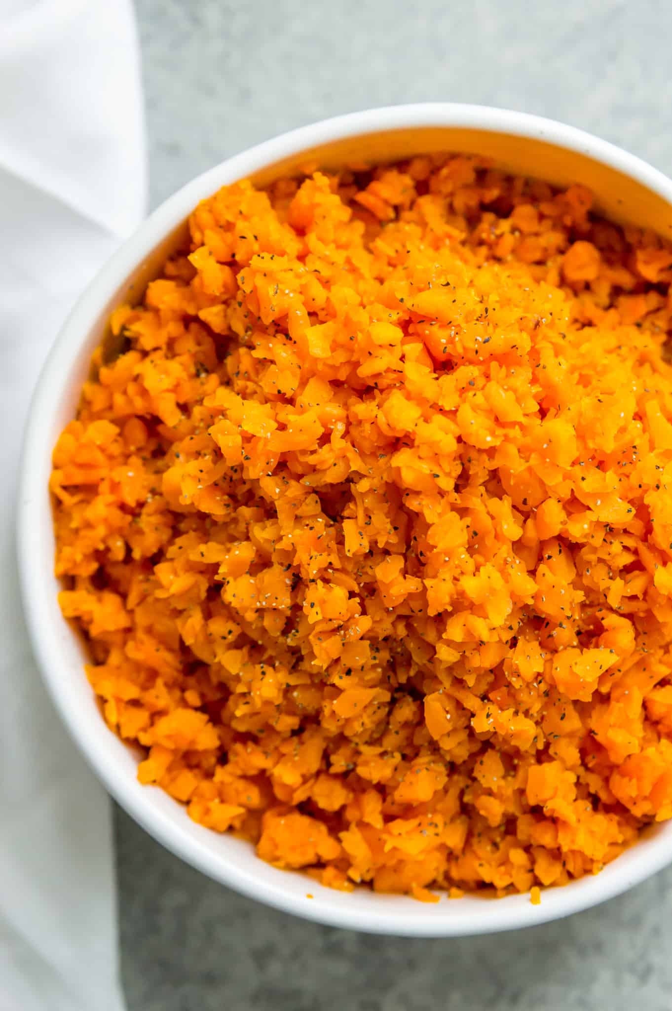 A white serving bowl of seasoned sweet potato rice 