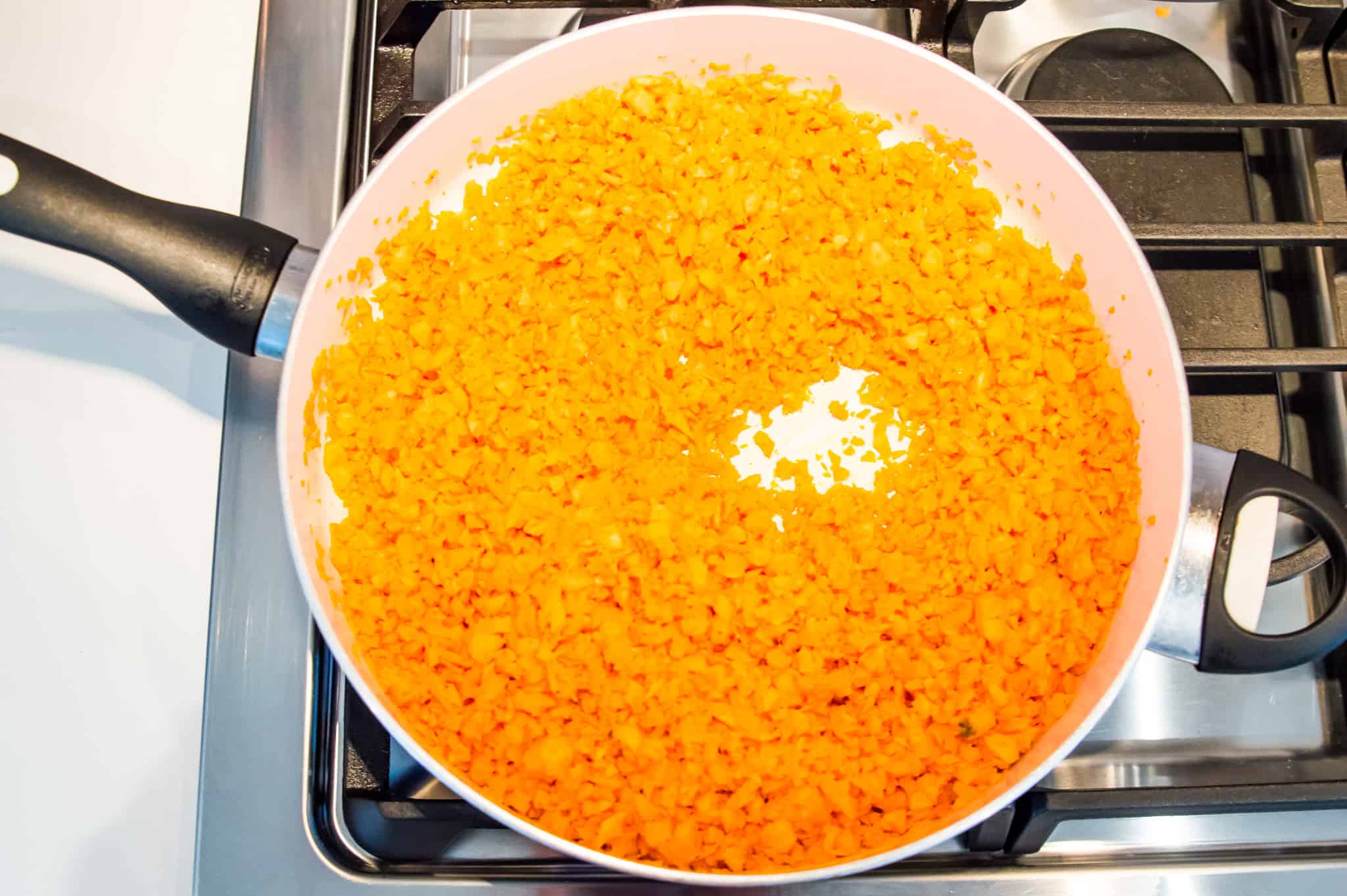 Sweet potato rice being cooked in a large pan on the stovetop.