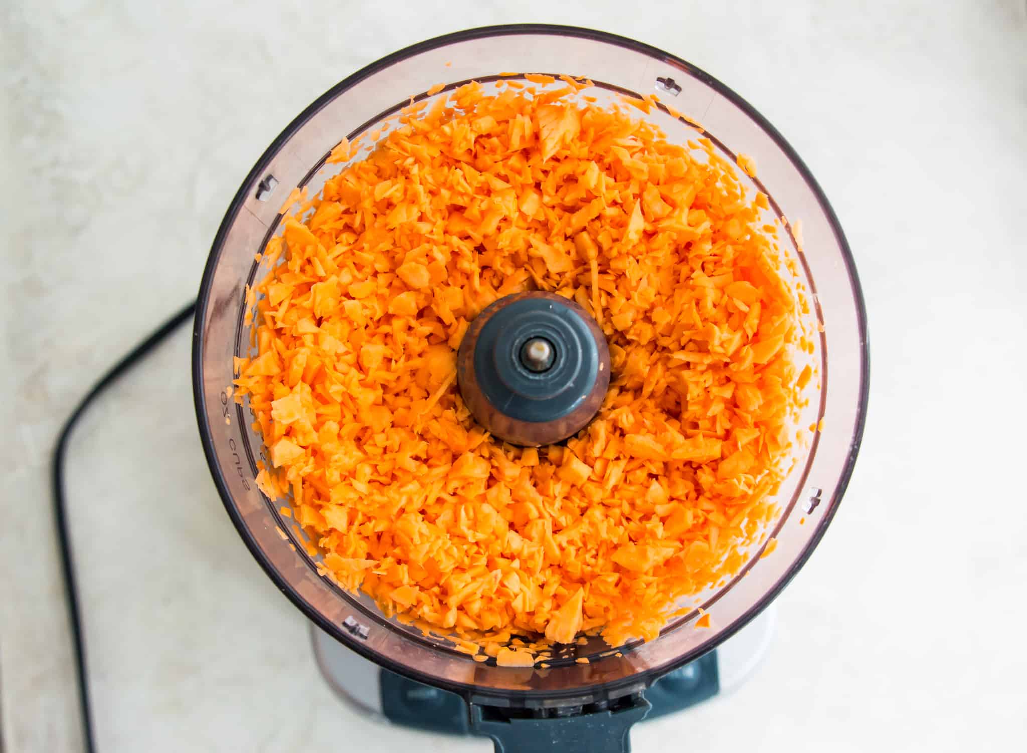 A food processor filled with small pieces of sweet potato.