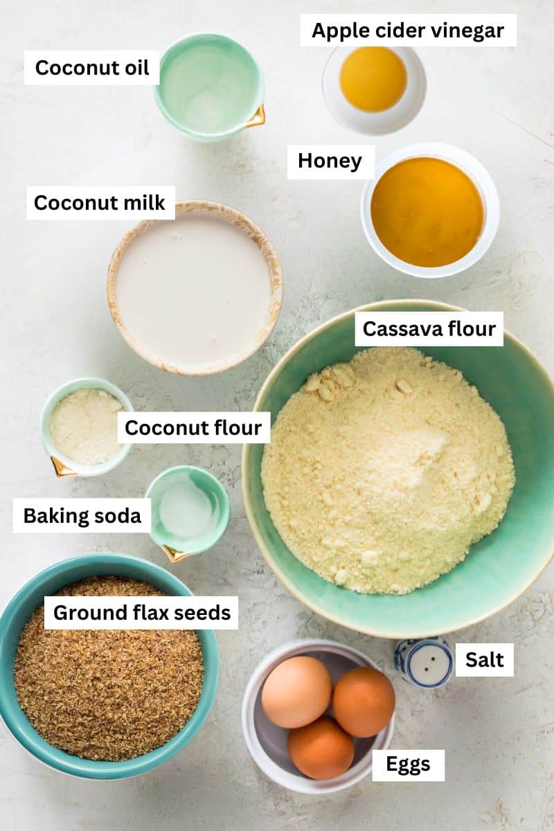 The ingredients for making bread separated into bowls including flour, flax seeds, honey, coconut oil, eggs and baking soda.