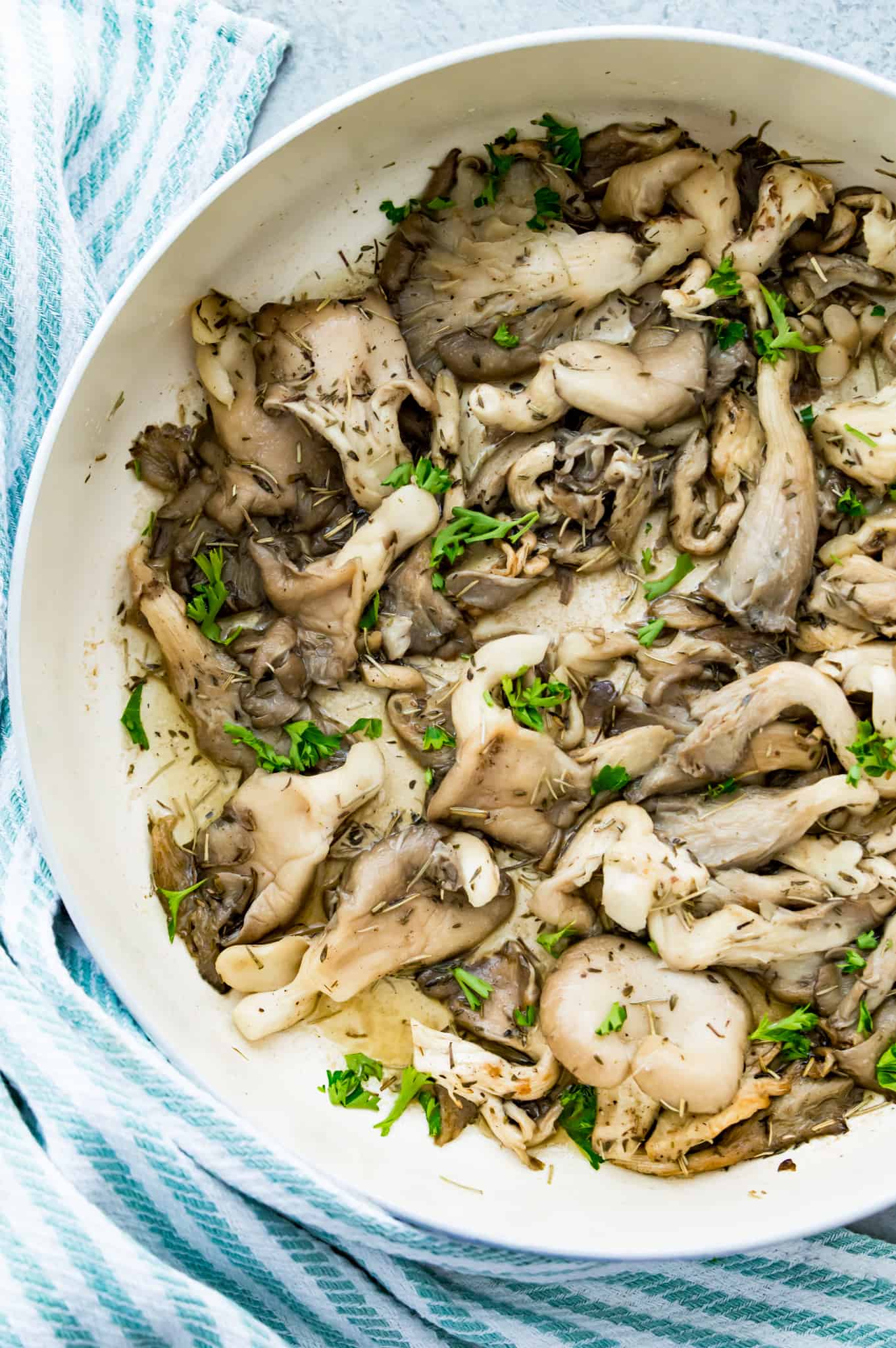 A pan filled with fried oyster mushrooms topped with fresh herbs. 
