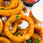 A plate of cooked onion rings with ketchup