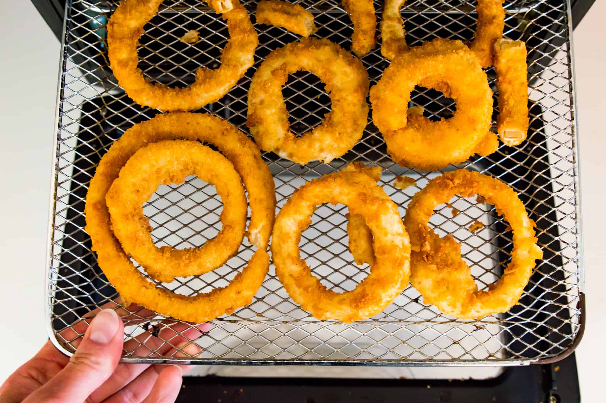 Frozen onion rings on an air fryer rack.