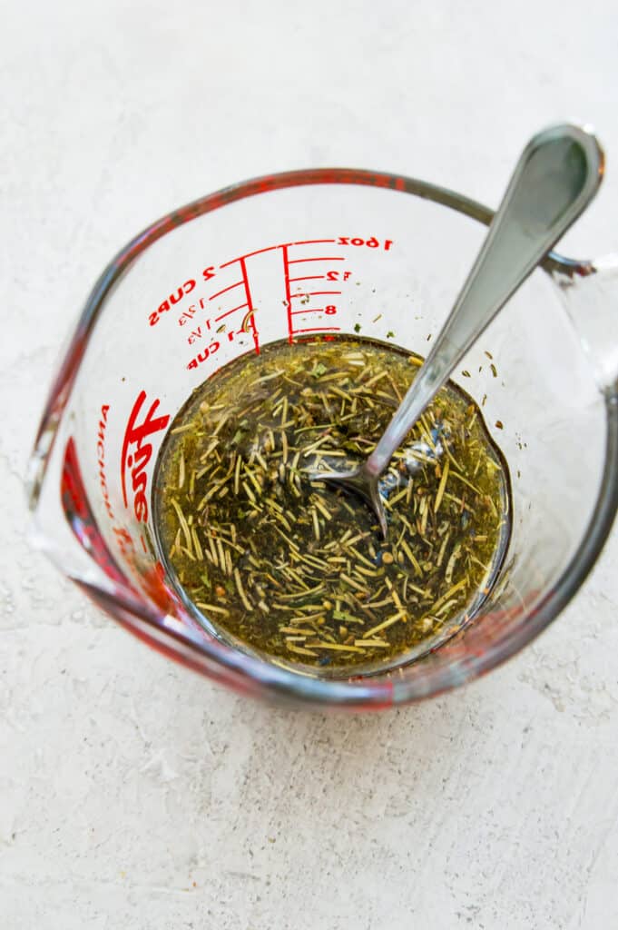 A glass measuring cup filled with the ingredients to make a steak marinade. 