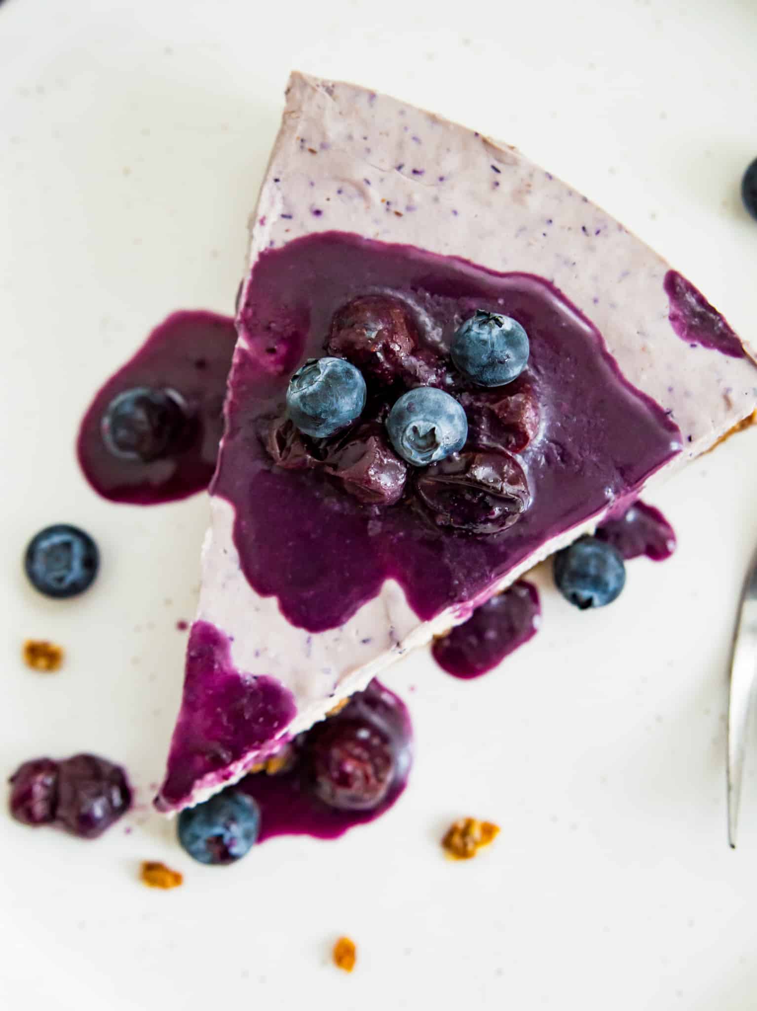 Overhead shot of a slice of cheesecake topped with fresh blueberries and blueberry sauce