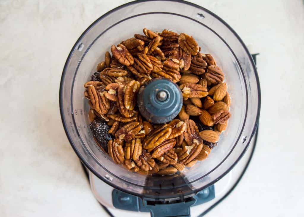 A food processor filled with pecans and almonds.