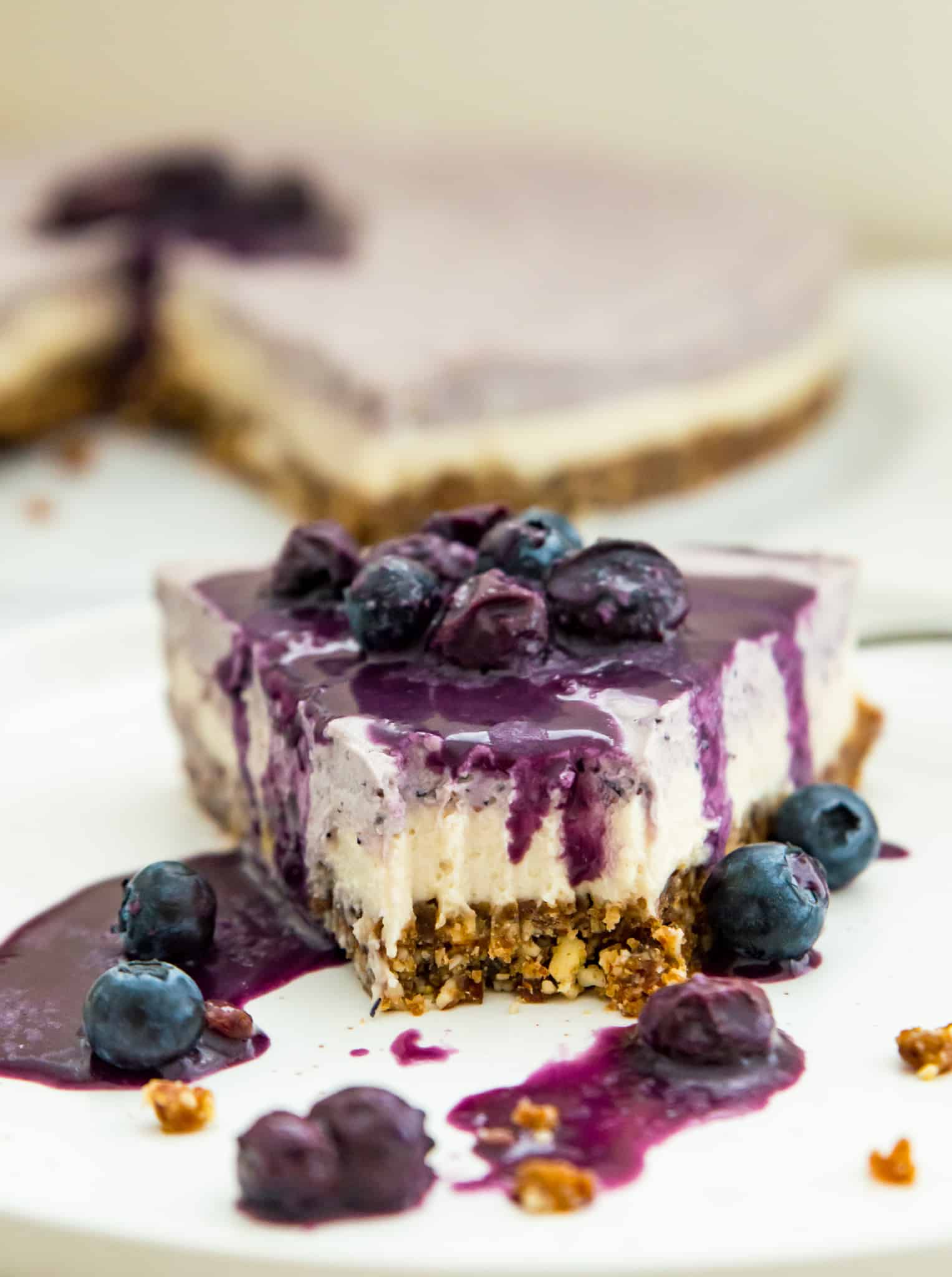 A slice of vegan cheesecake covered in blueberry sauce with a bite taken out.