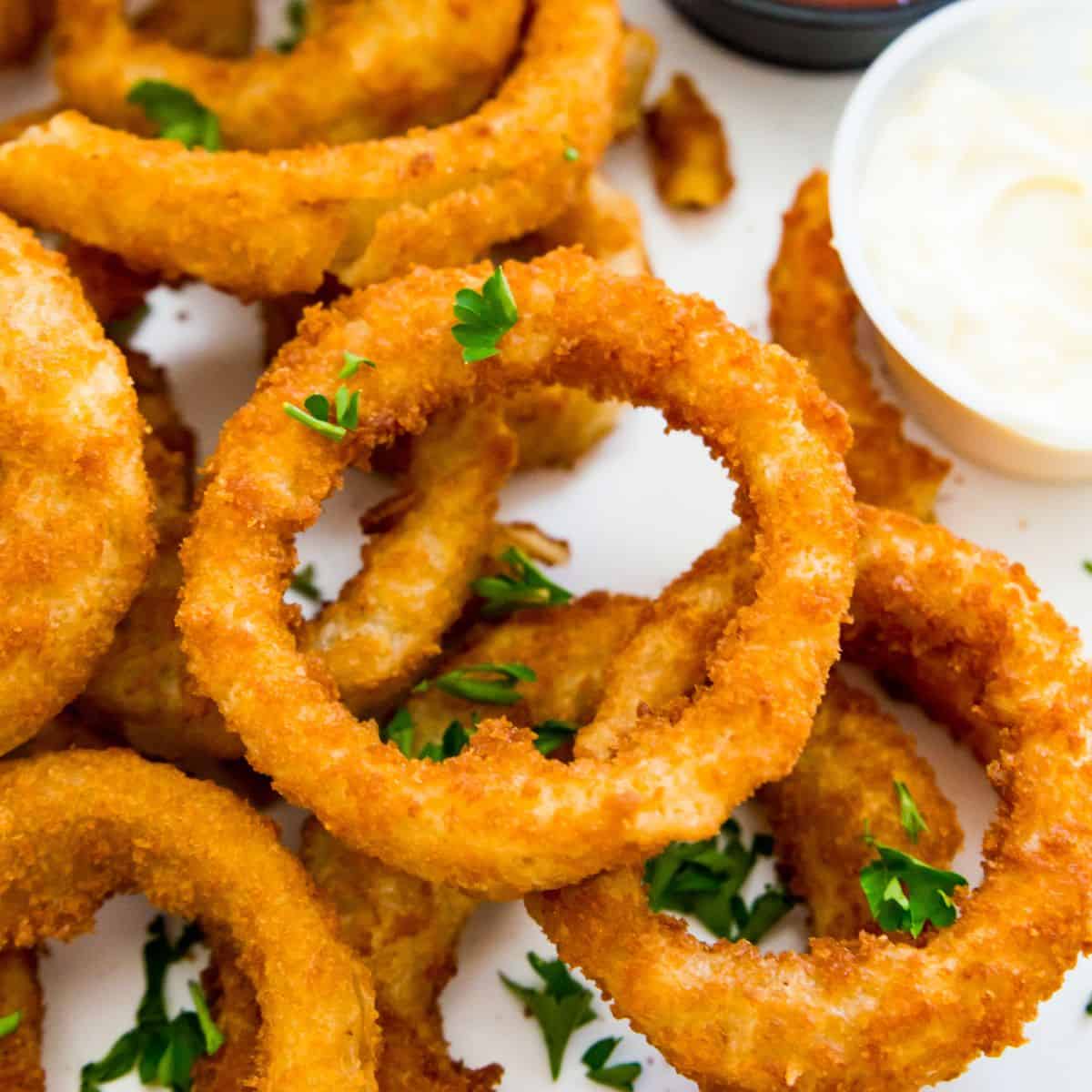 A plate of cooked onion rings garnished with fresh parsley.