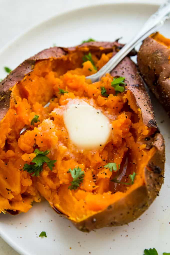 A baked sweet potato topped with butter and herbs 