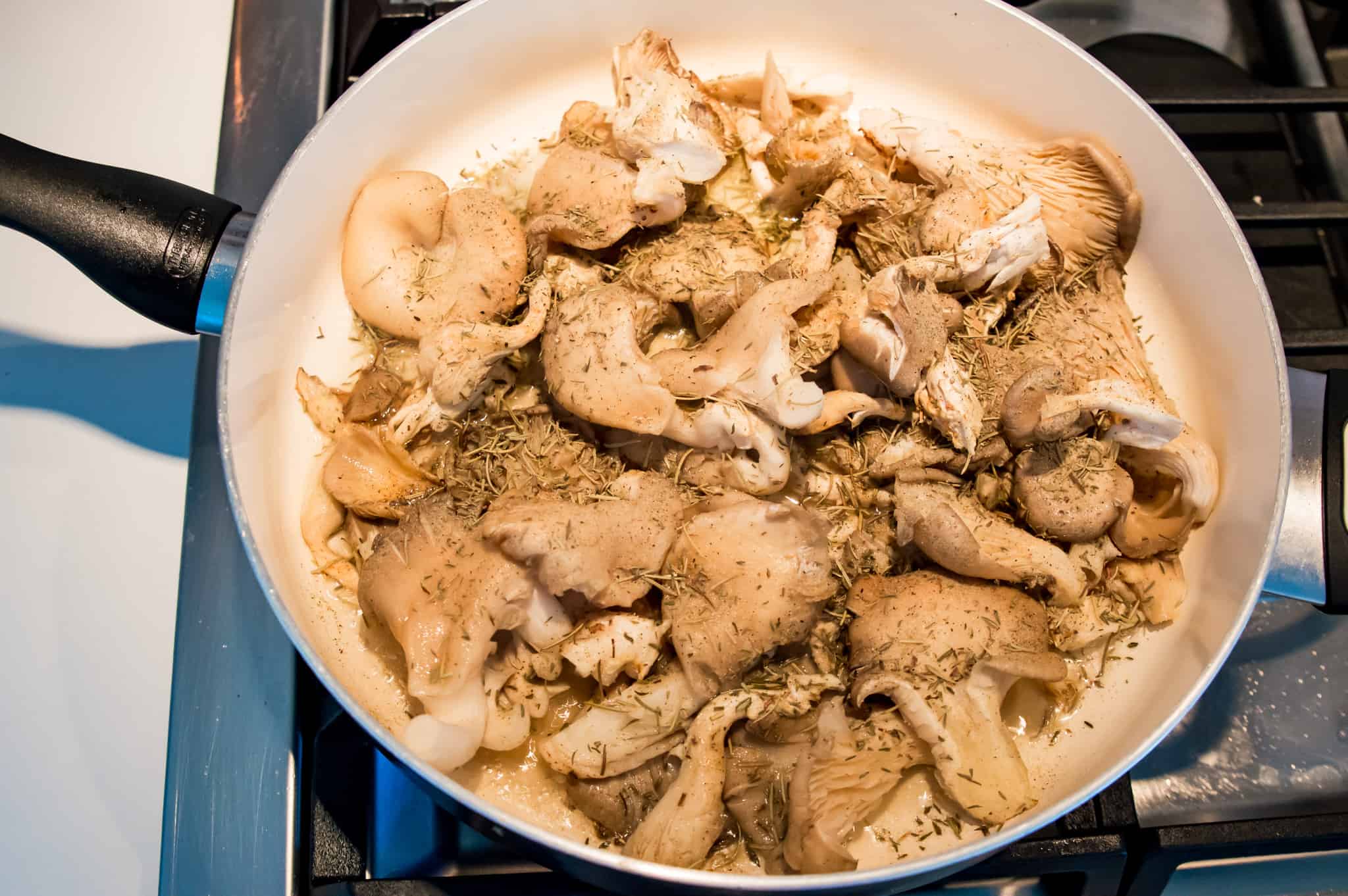 A pan on the stovetop filled with oyster mushrooms and spices.