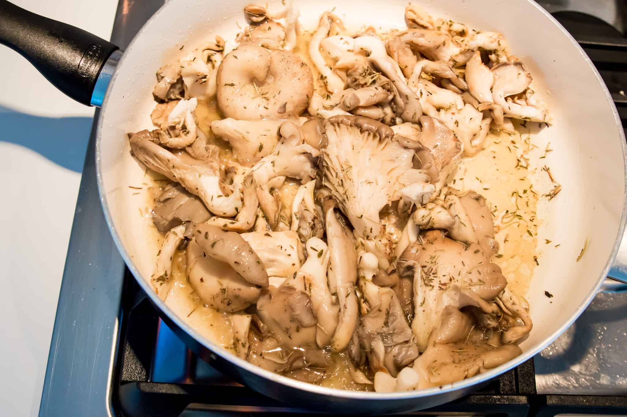 Oyster mushrooms cooking in a pan on the stovetop.