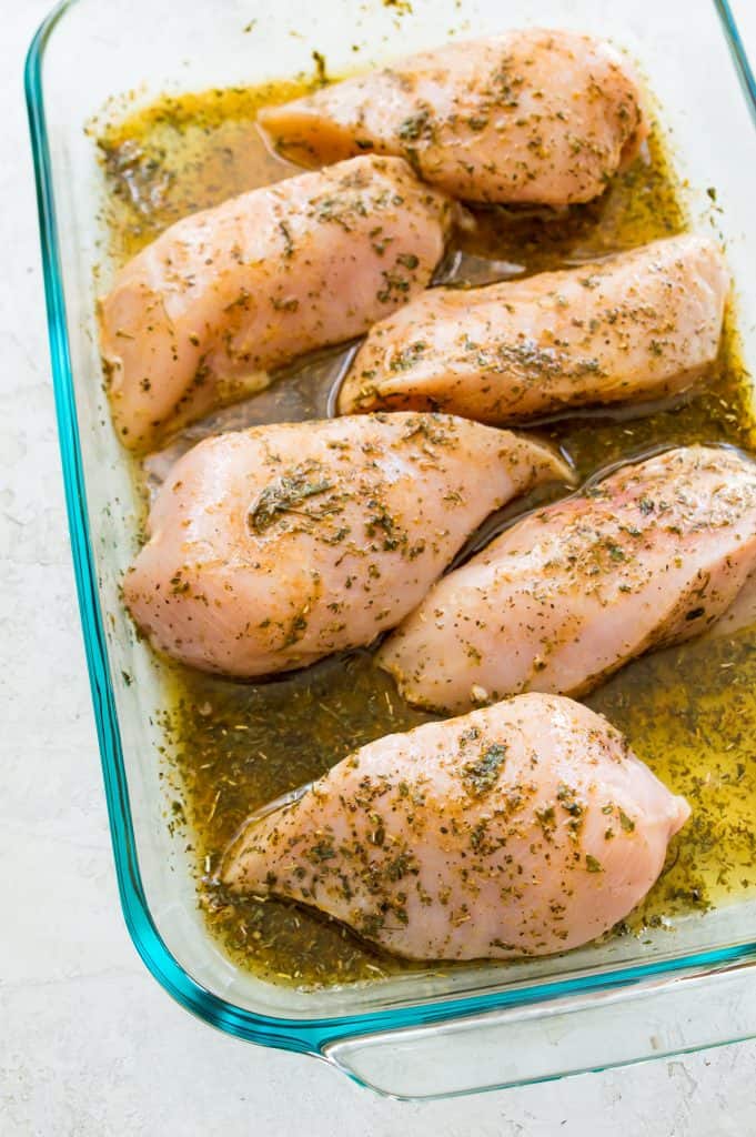 Chicken breasts in a glass baking dish marinading in a Mexican marinade. 