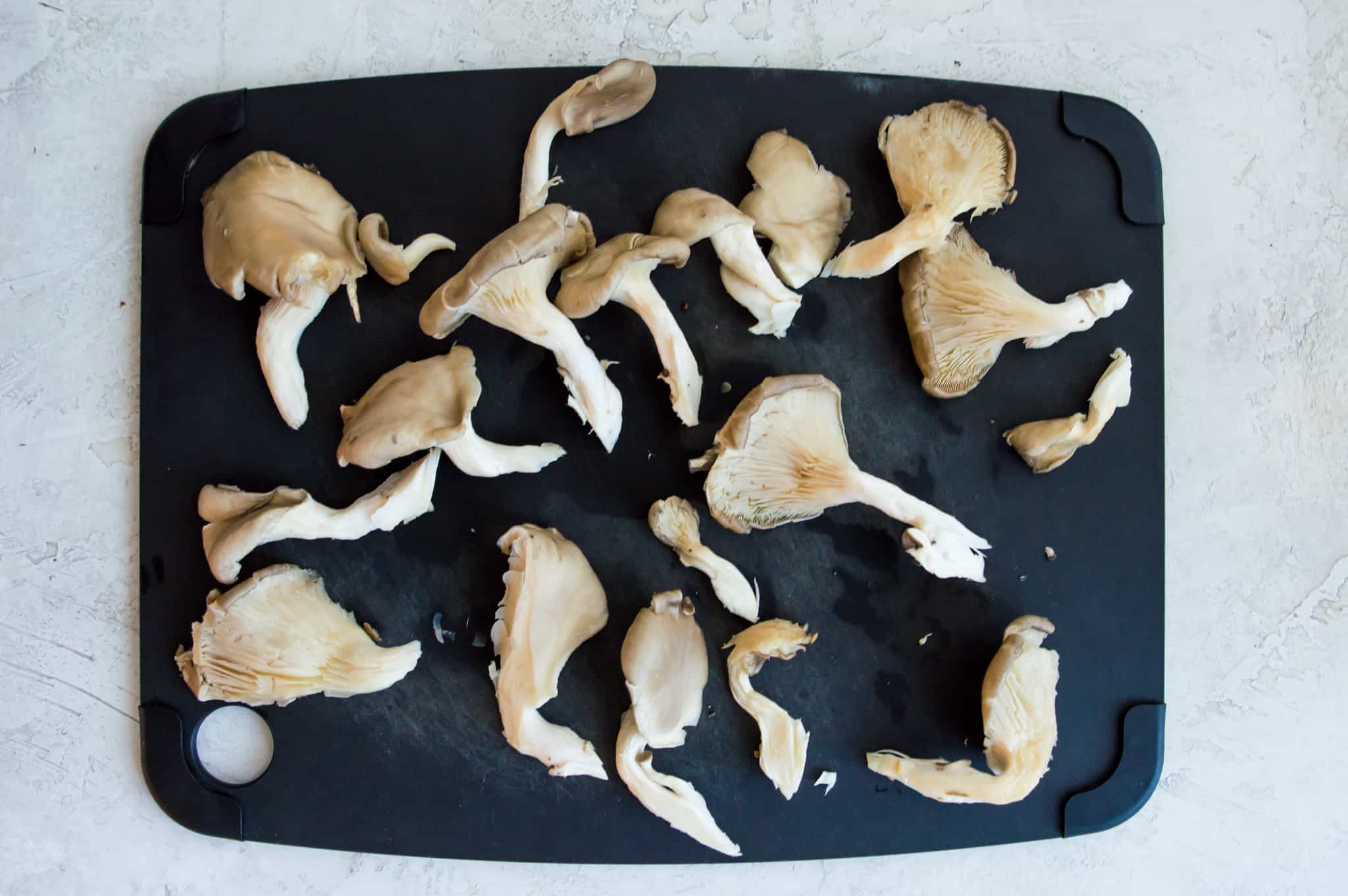 Cut up oyster mushrooms on a cutting board.
