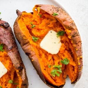 An air fryer baked sweet potato, cut in half with butter on it.