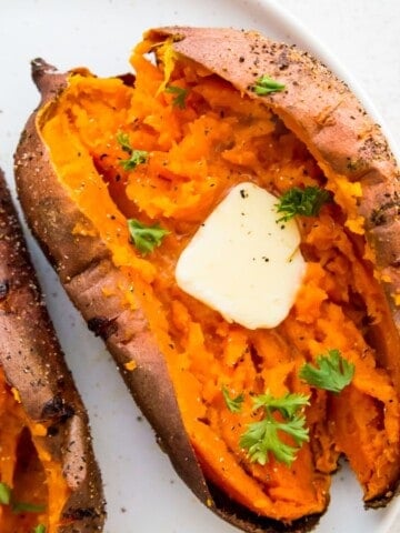 An air fryer baked sweet potato, cut in half with butter on it.