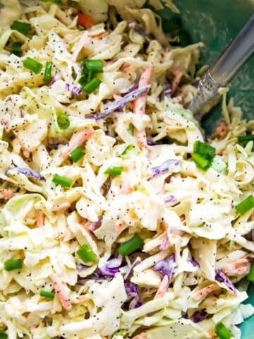 A bowl of keto coleslaw with a spoon in it.
