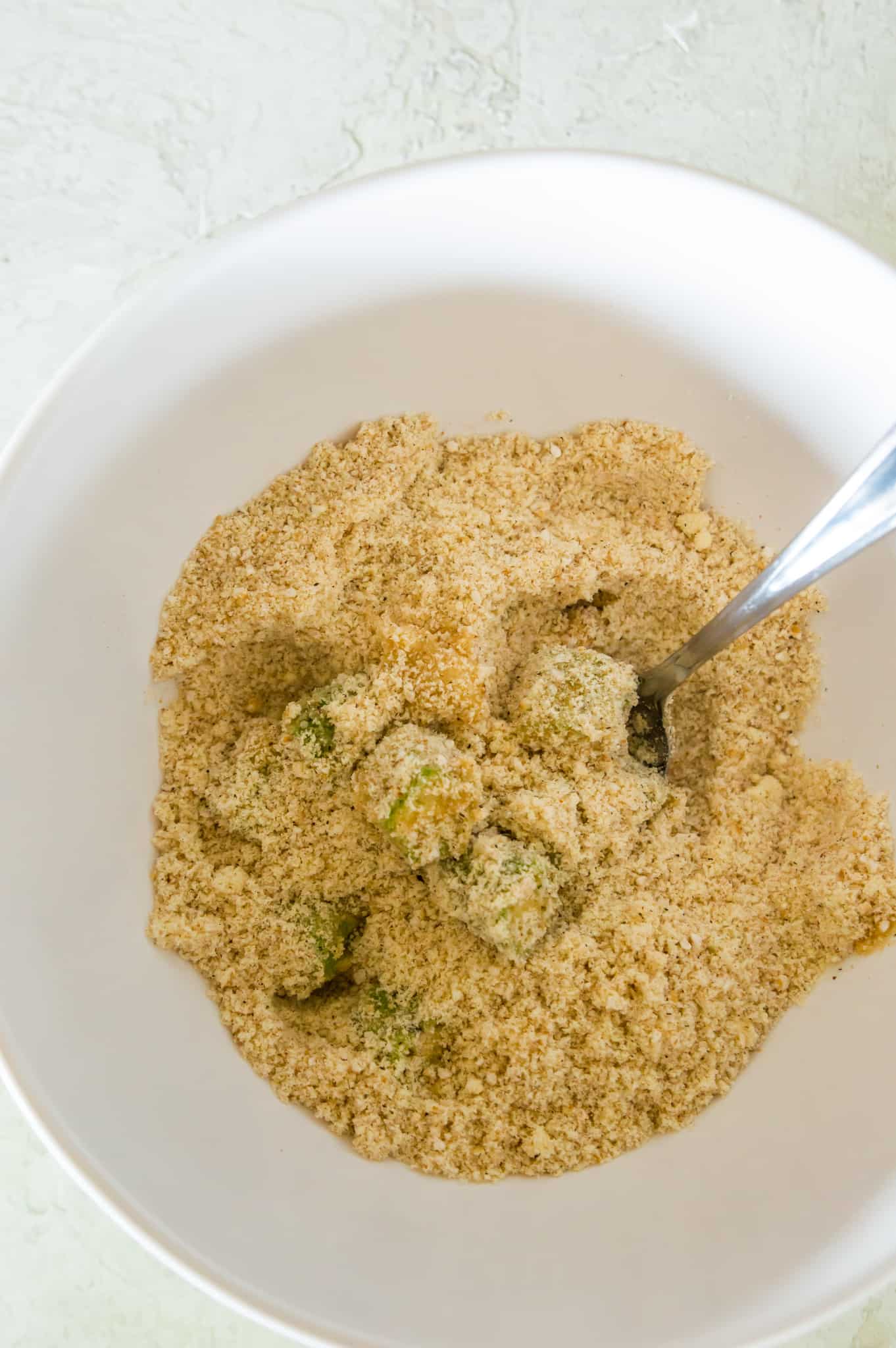 Okra pieces in a bowl of breadcrumbs. 
