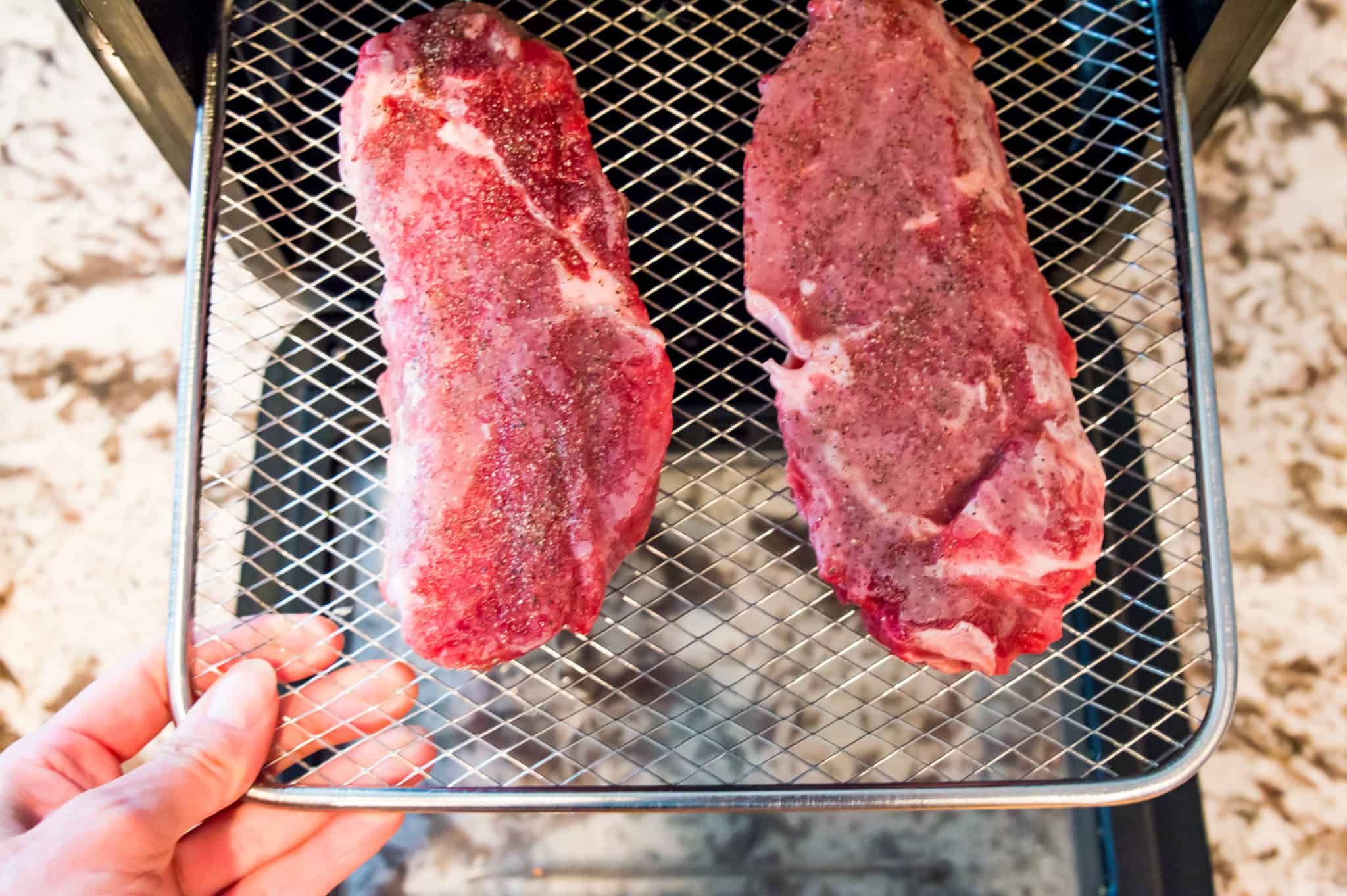 Two frozen steaks on an air fryer rack.