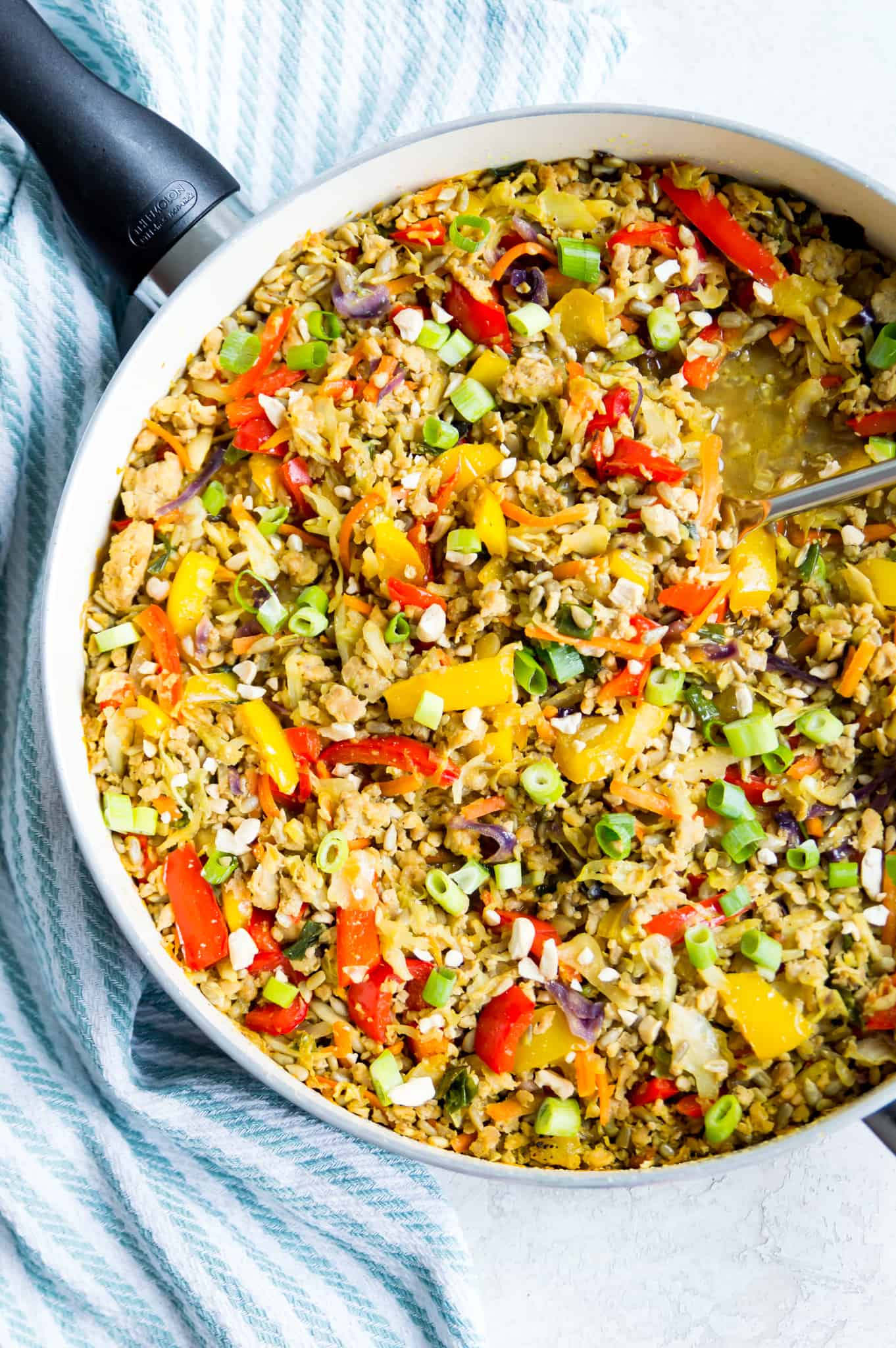 A pan of egg roll in a bowl topped with chopped green onion and crushed peanuts. 