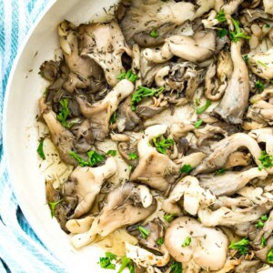 A pan of fried oyster mushrooms topped with fresh herbs.