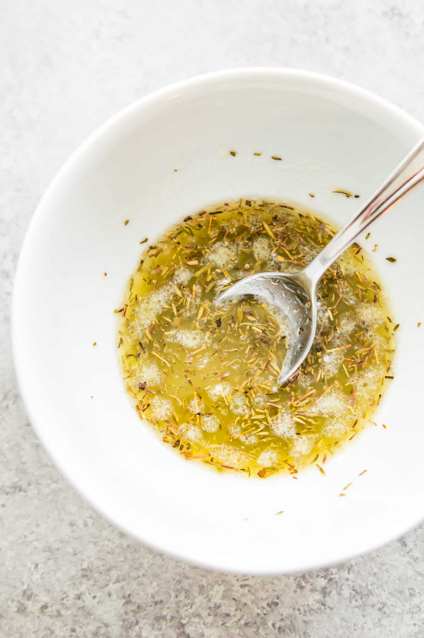A bowl full of a lemon butter sauce with a spoon in it.